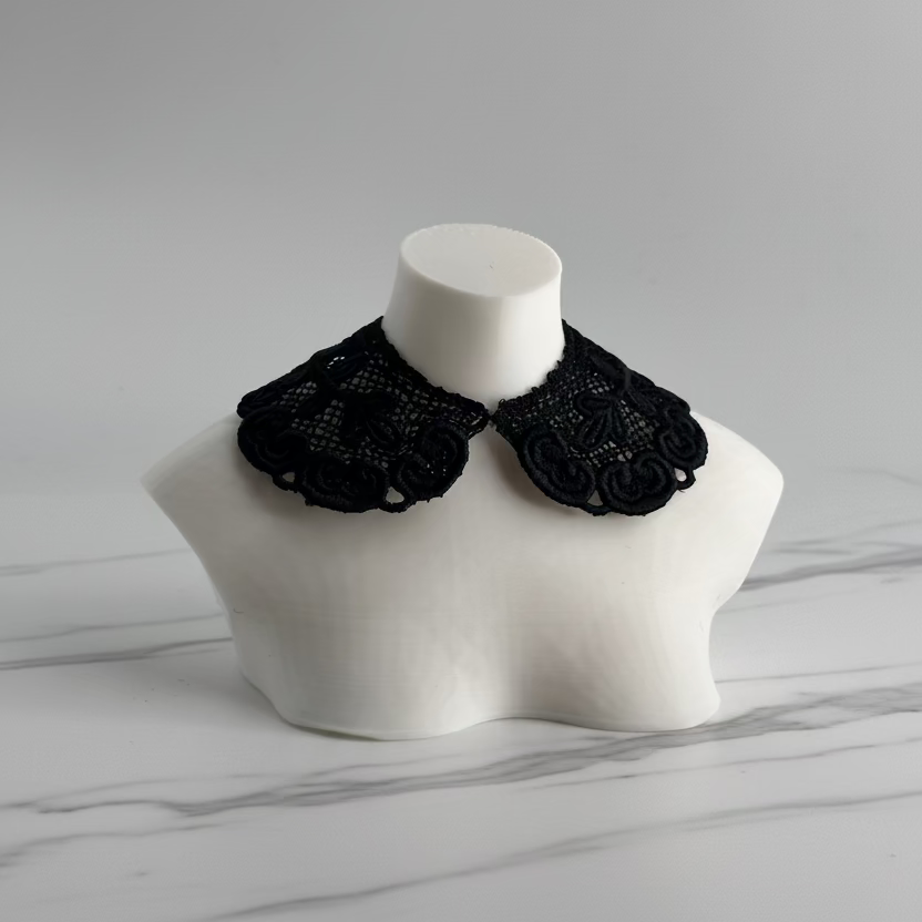 A black lace doll collar displayed on a white mannequin bust against a light gray background.